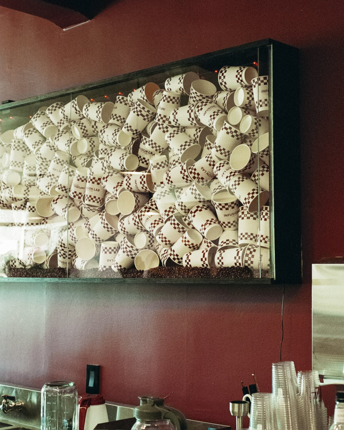 Framed installation of Infusion Lab checkerboard cups above the bar
