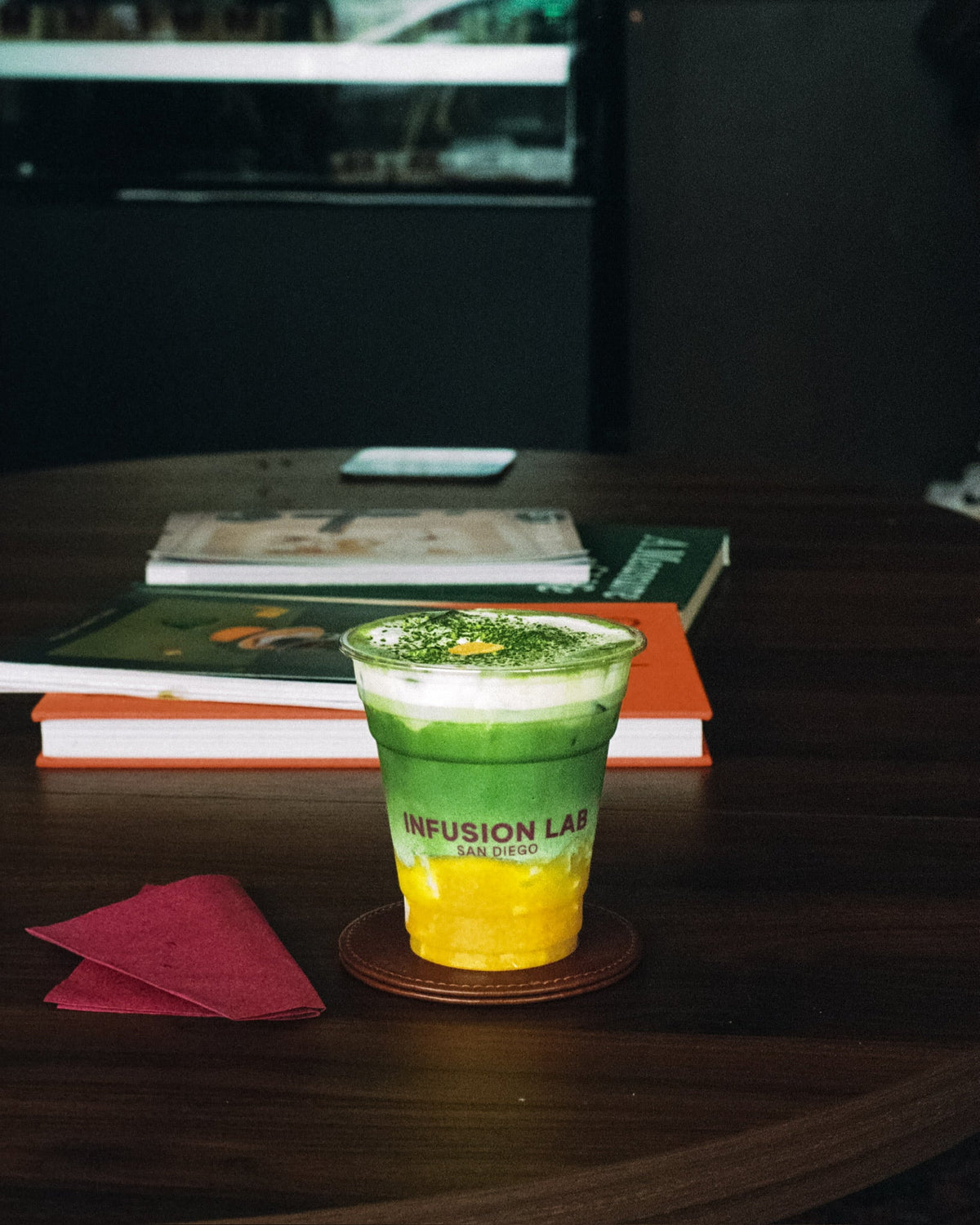 A layered matcha drink on a wooden table beside books
