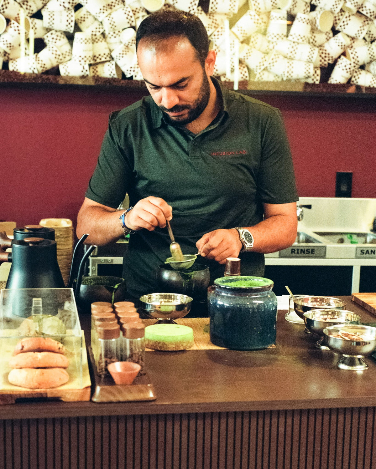 A member of the Infusion Lab team sifting matcha at the coffee bar.